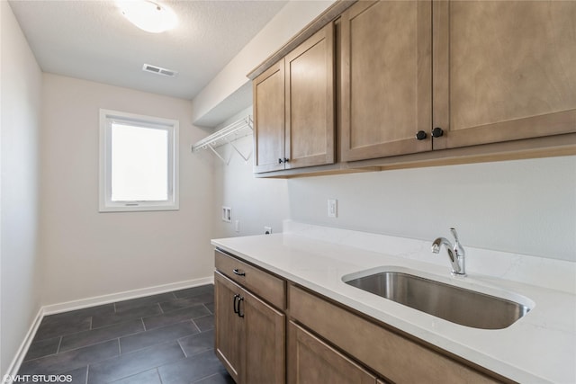 kitchen with sink, light stone countertops, a textured ceiling, and dark tile patterned flooring