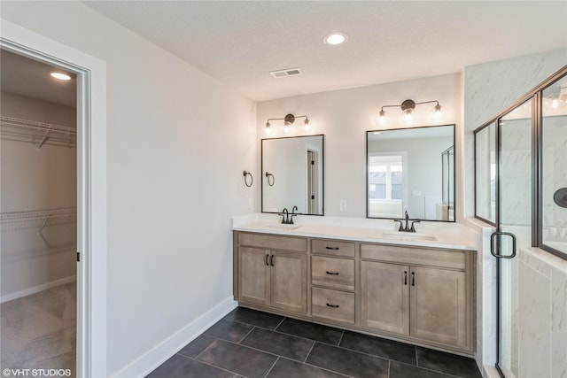 bathroom featuring vanity, a textured ceiling, an enclosed shower, and tile patterned floors