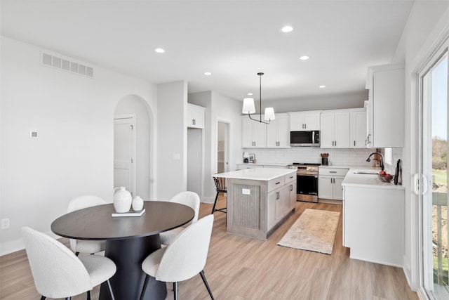 kitchen featuring pendant lighting, appliances with stainless steel finishes, white cabinets, and a kitchen island