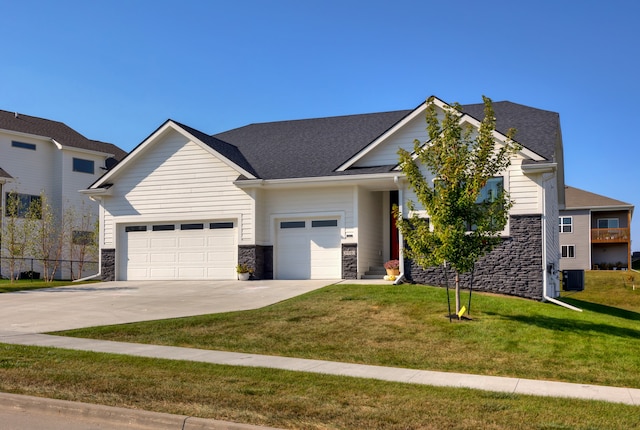 view of front of home with a front yard, a garage, and central air condition unit