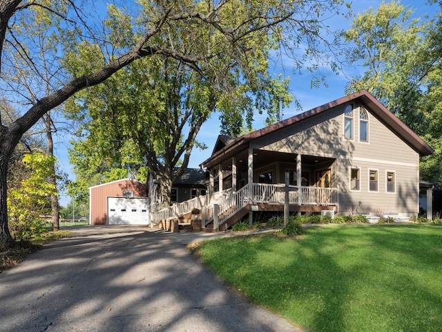 view of front of house featuring a front yard, a garage, covered porch, and an outbuilding