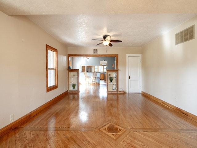 unfurnished living room featuring ceiling fan, a textured ceiling, and hardwood / wood-style floors