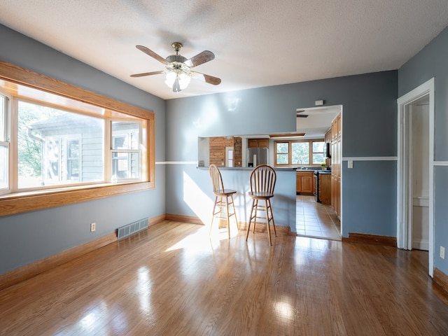 interior space with ceiling fan, light hardwood / wood-style flooring, and a textured ceiling