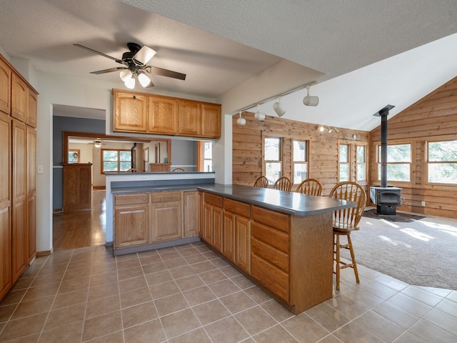 kitchen featuring light tile patterned floors, kitchen peninsula, a wood stove, and a breakfast bar