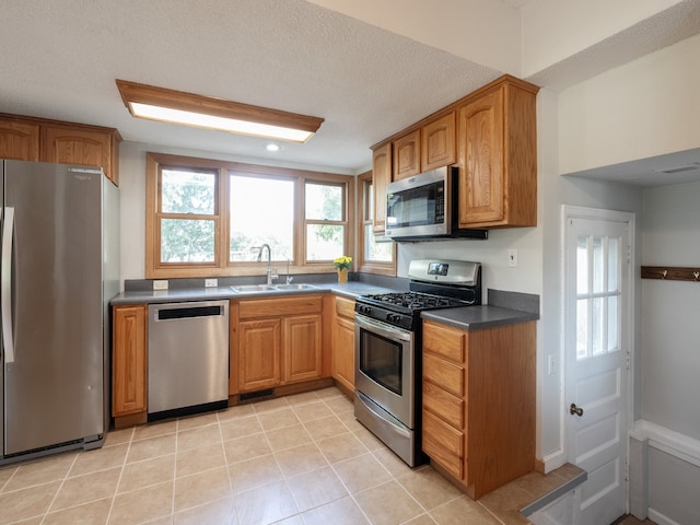 kitchen featuring a textured ceiling, appliances with stainless steel finishes, sink, and light tile patterned flooring