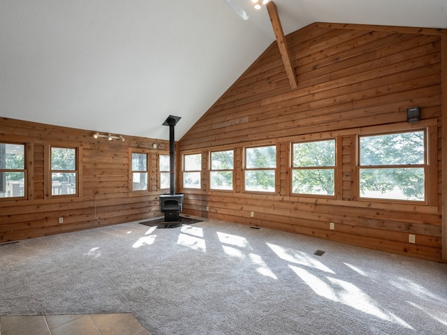 unfurnished living room with a wood stove, light carpet, and a wealth of natural light