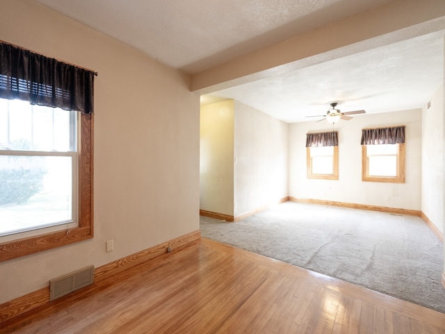 unfurnished room featuring a textured ceiling, ceiling fan, and light hardwood / wood-style flooring