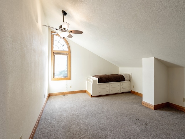 additional living space with ceiling fan, light carpet, vaulted ceiling, and a textured ceiling