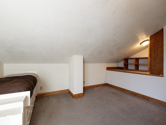 unfurnished bedroom with vaulted ceiling, carpet, and a textured ceiling