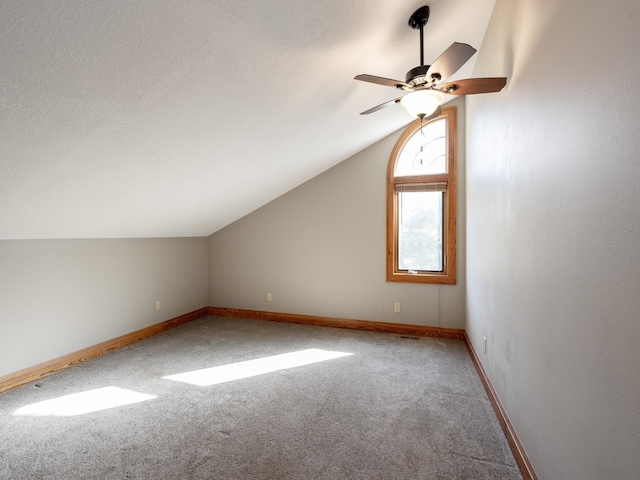 additional living space with lofted ceiling, carpet flooring, a textured ceiling, and ceiling fan