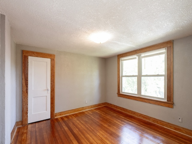 empty room with hardwood / wood-style flooring and a textured ceiling