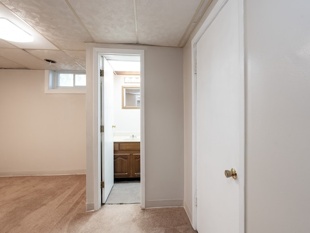 hall with sink and light colored carpet