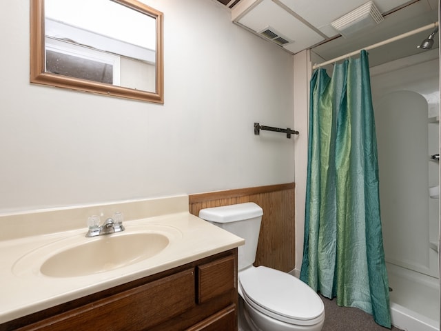 bathroom with walk in shower, vanity, wood walls, and toilet