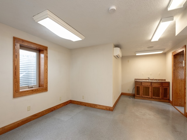 empty room featuring an AC wall unit, sink, and a textured ceiling