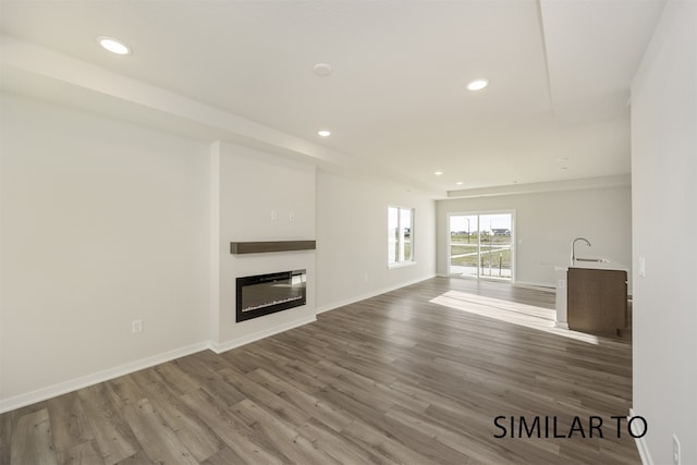 unfurnished living room with hardwood / wood-style floors and sink