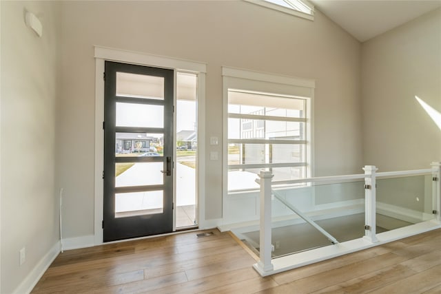 doorway to outside featuring wood-type flooring and vaulted ceiling