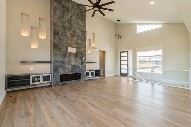 unfurnished living room featuring a tile fireplace, high vaulted ceiling, light hardwood / wood-style flooring, and ceiling fan