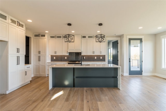 kitchen with pendant lighting, an island with sink, light hardwood / wood-style floors, and sink