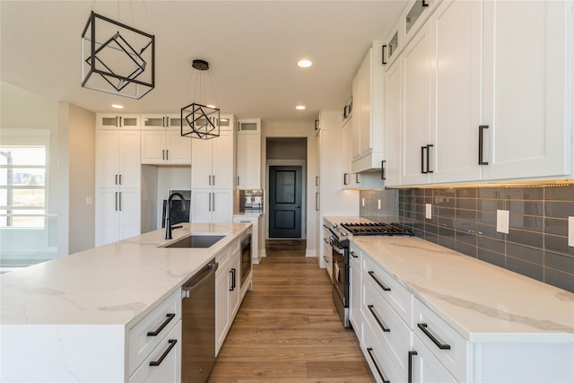 kitchen featuring light wood-type flooring, stainless steel appliances, white cabinets, sink, and hanging light fixtures