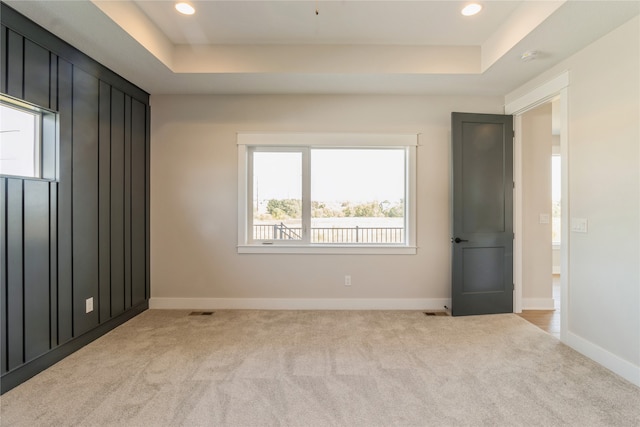 carpeted spare room featuring a tray ceiling