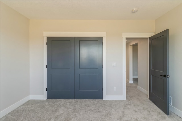 unfurnished bedroom featuring light carpet and a closet