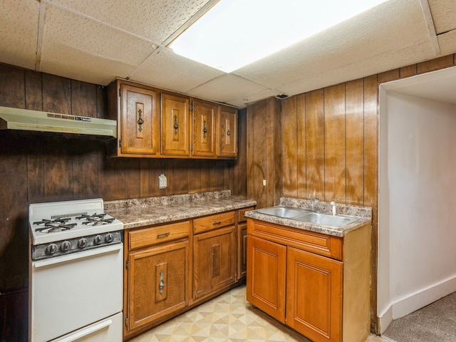 kitchen featuring white gas range, wood walls, sink, and extractor fan