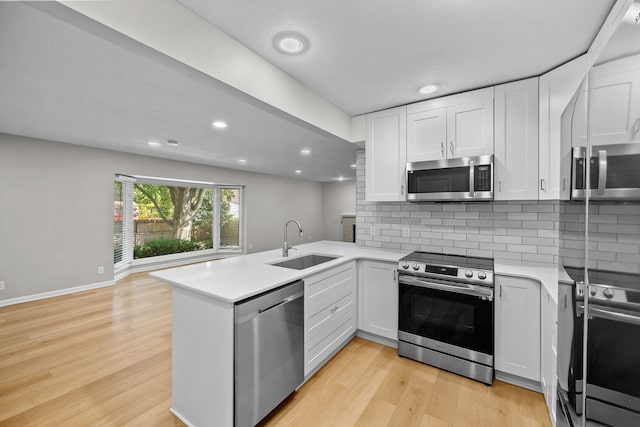 kitchen with kitchen peninsula, tasteful backsplash, stainless steel appliances, sink, and white cabinetry