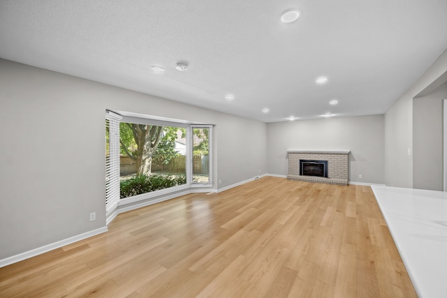 unfurnished living room with a fireplace, a textured ceiling, and light hardwood / wood-style flooring