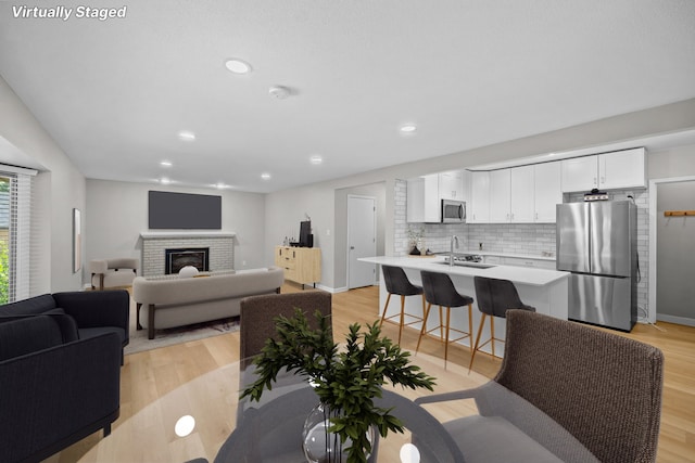 living room with light wood-type flooring, sink, and a brick fireplace