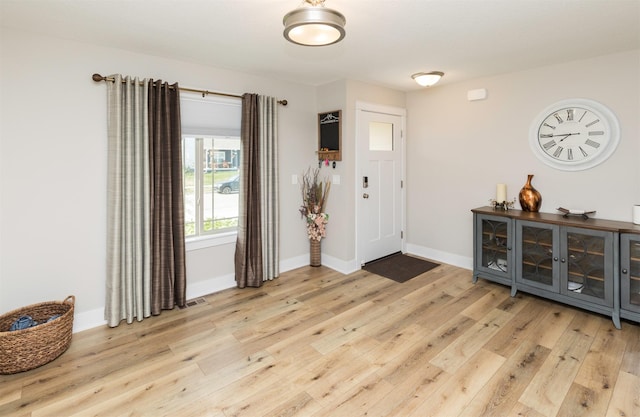 foyer entrance with light wood-style flooring and baseboards