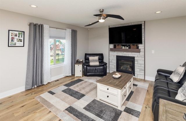 living area with light wood-style flooring, a ceiling fan, recessed lighting, a fireplace, and baseboards