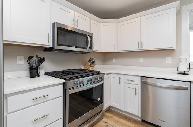 kitchen with stainless steel appliances, light wood finished floors, light countertops, and white cabinetry