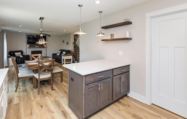 kitchen featuring light countertops, a fireplace, light wood-style floors, and pendant lighting