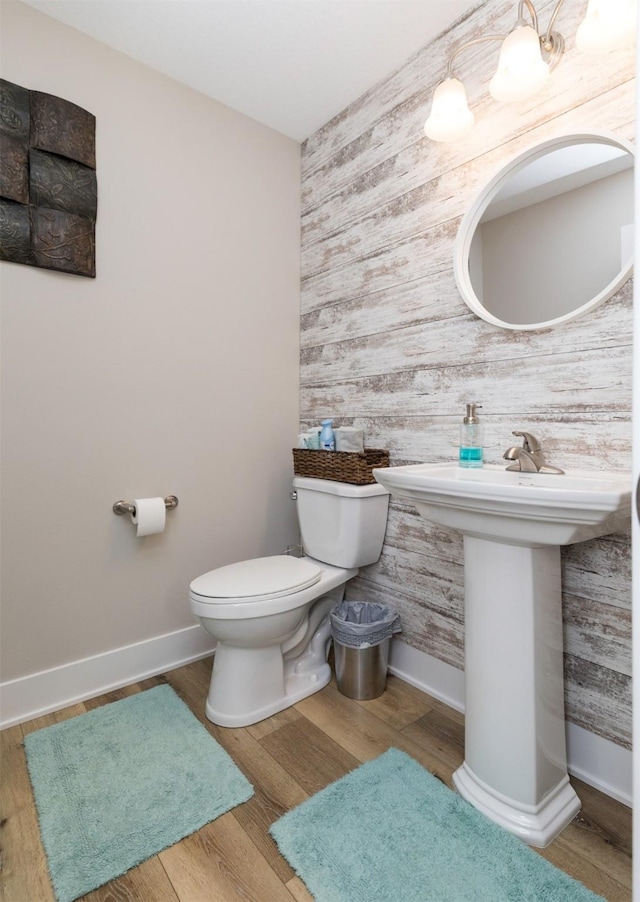 bathroom featuring wallpapered walls, toilet, baseboards, and wood finished floors