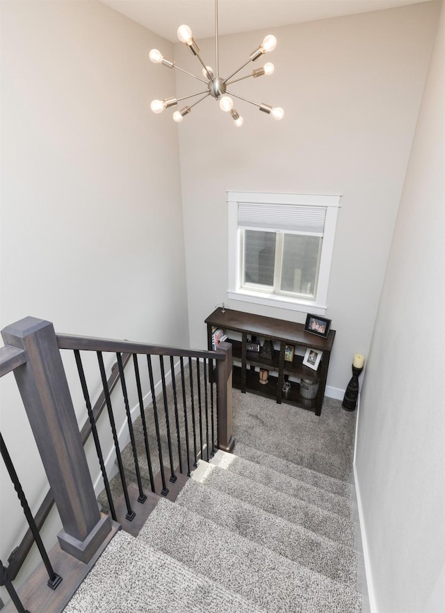 stairs featuring a notable chandelier, baseboards, and carpet floors