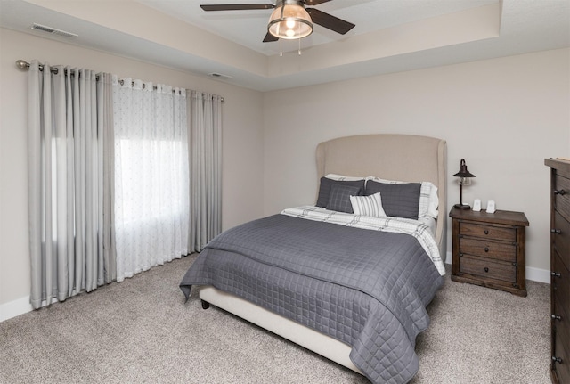 bedroom featuring a tray ceiling, carpet, and visible vents