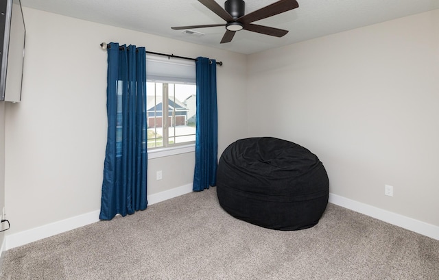 living area with baseboards, visible vents, carpet floors, ceiling fan, and a textured ceiling