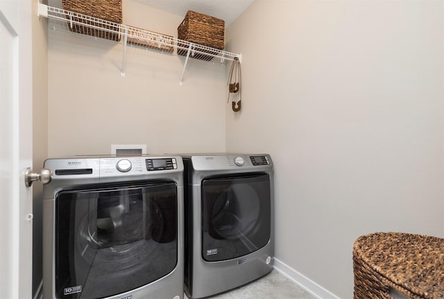 washroom with baseboards, separate washer and dryer, and laundry area