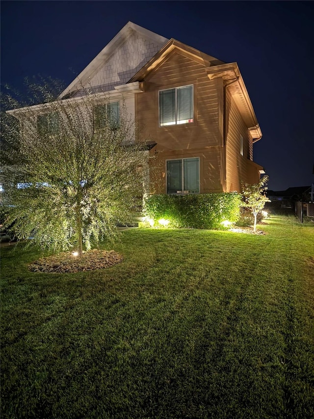 property exterior at night featuring a yard