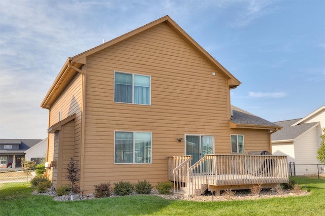 back of house featuring a wooden deck, a yard, and fence