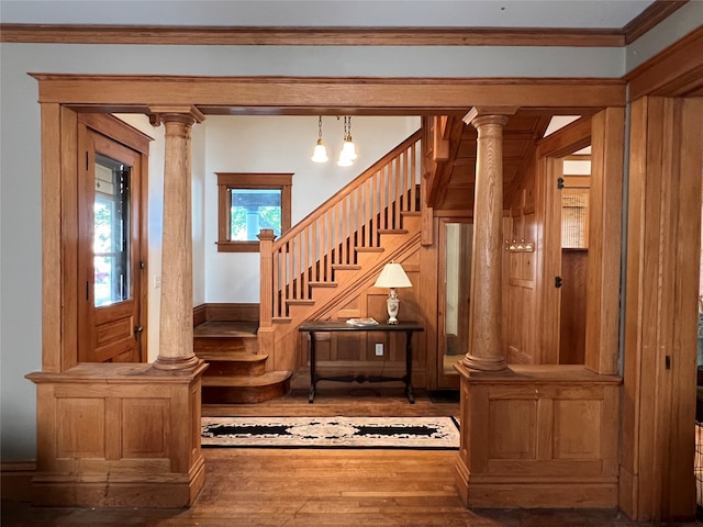 staircase featuring ornamental molding, decorative columns, and wood-type flooring