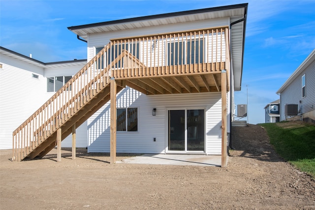 back of house with a wooden deck and a patio