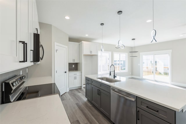 kitchen with white cabinets, pendant lighting, sink, stainless steel appliances, and dark hardwood / wood-style floors