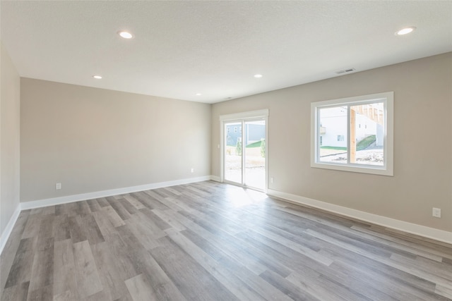 empty room with light wood-type flooring and a textured ceiling