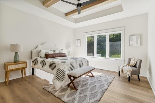 bedroom featuring a raised ceiling, ceiling fan, and light hardwood / wood-style floors