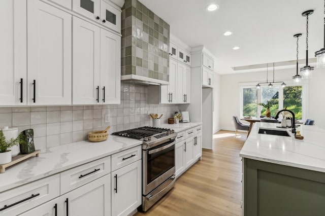 kitchen with gas range, sink, pendant lighting, light hardwood / wood-style flooring, and white cabinets