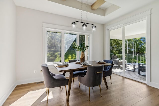 dining room featuring beamed ceiling and light hardwood / wood-style floors