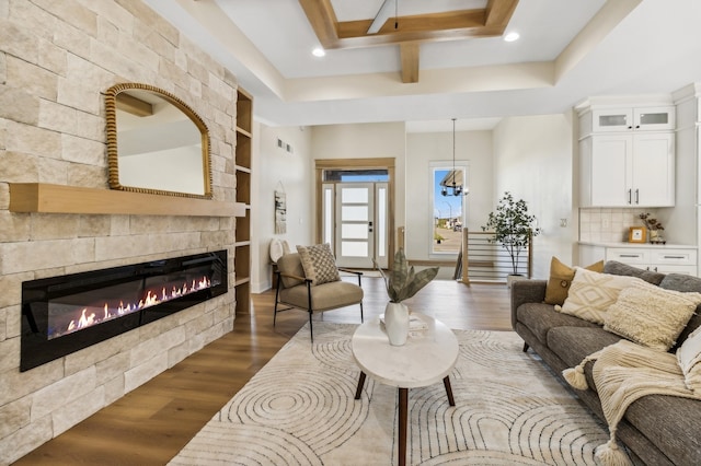 living room with a tile fireplace, built in features, and dark wood-type flooring