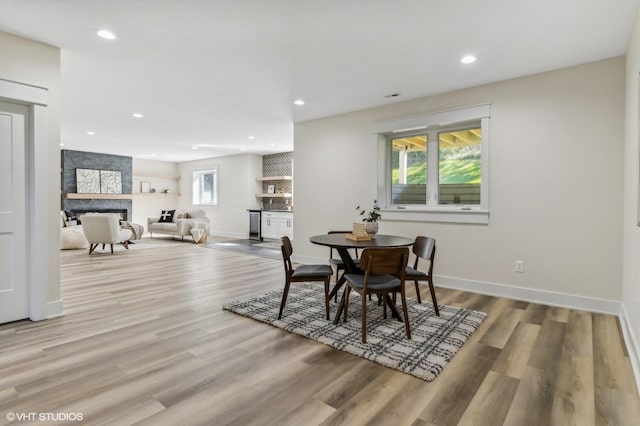 dining area with a fireplace and light hardwood / wood-style flooring