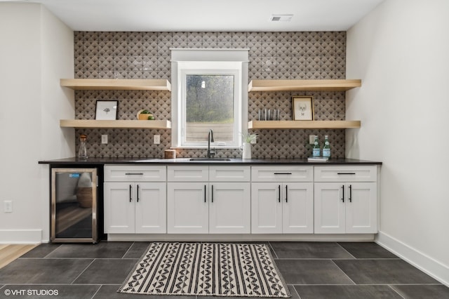 bar with white cabinets, beverage cooler, and sink